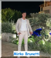 Foto del concorrente Mirko Brunetti mentre posa in abito bianco